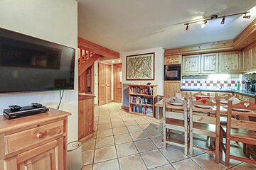 A living room with a dining table and chairs and a flat screen tv