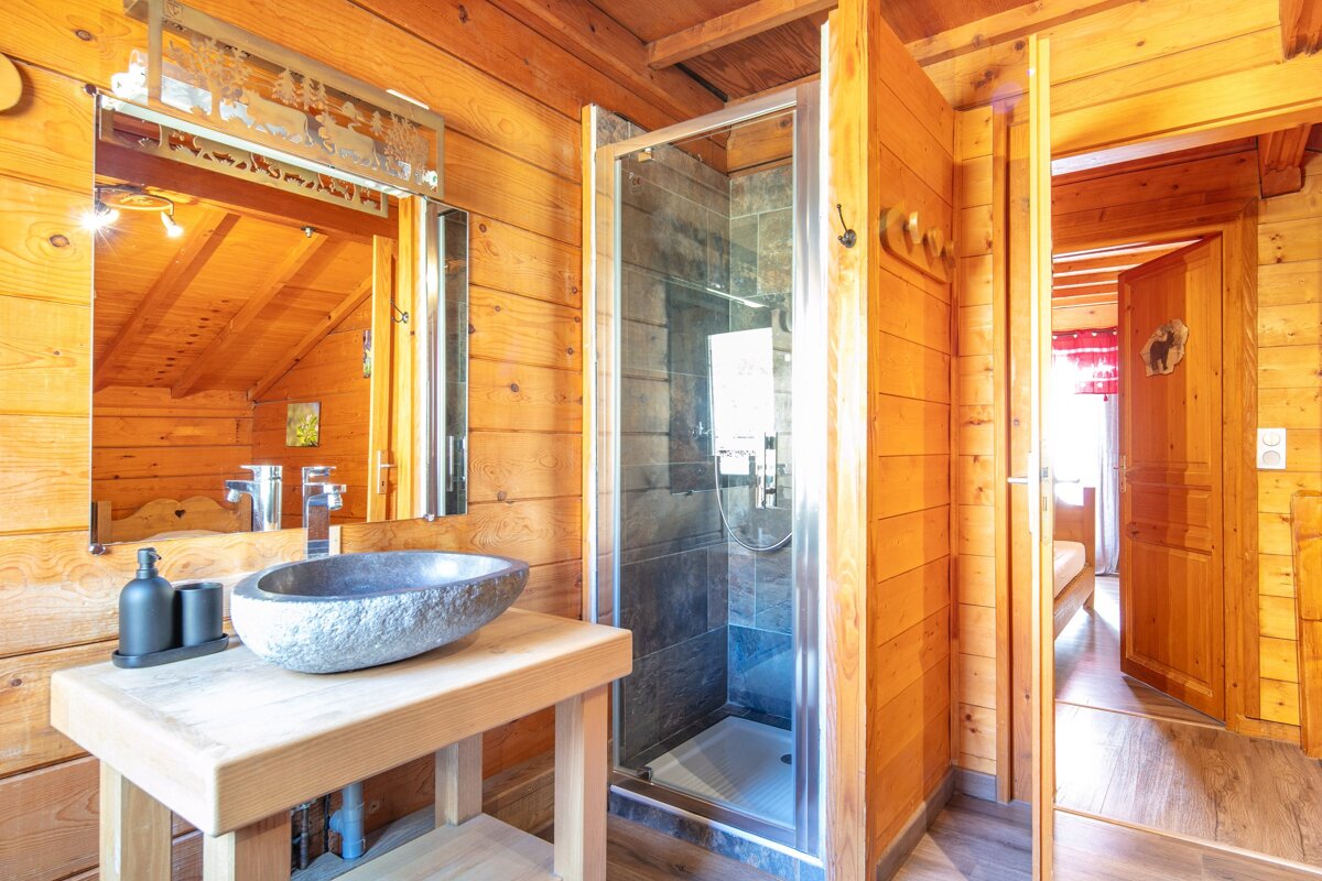 A bathroom in a log cabin with a sink and a shower