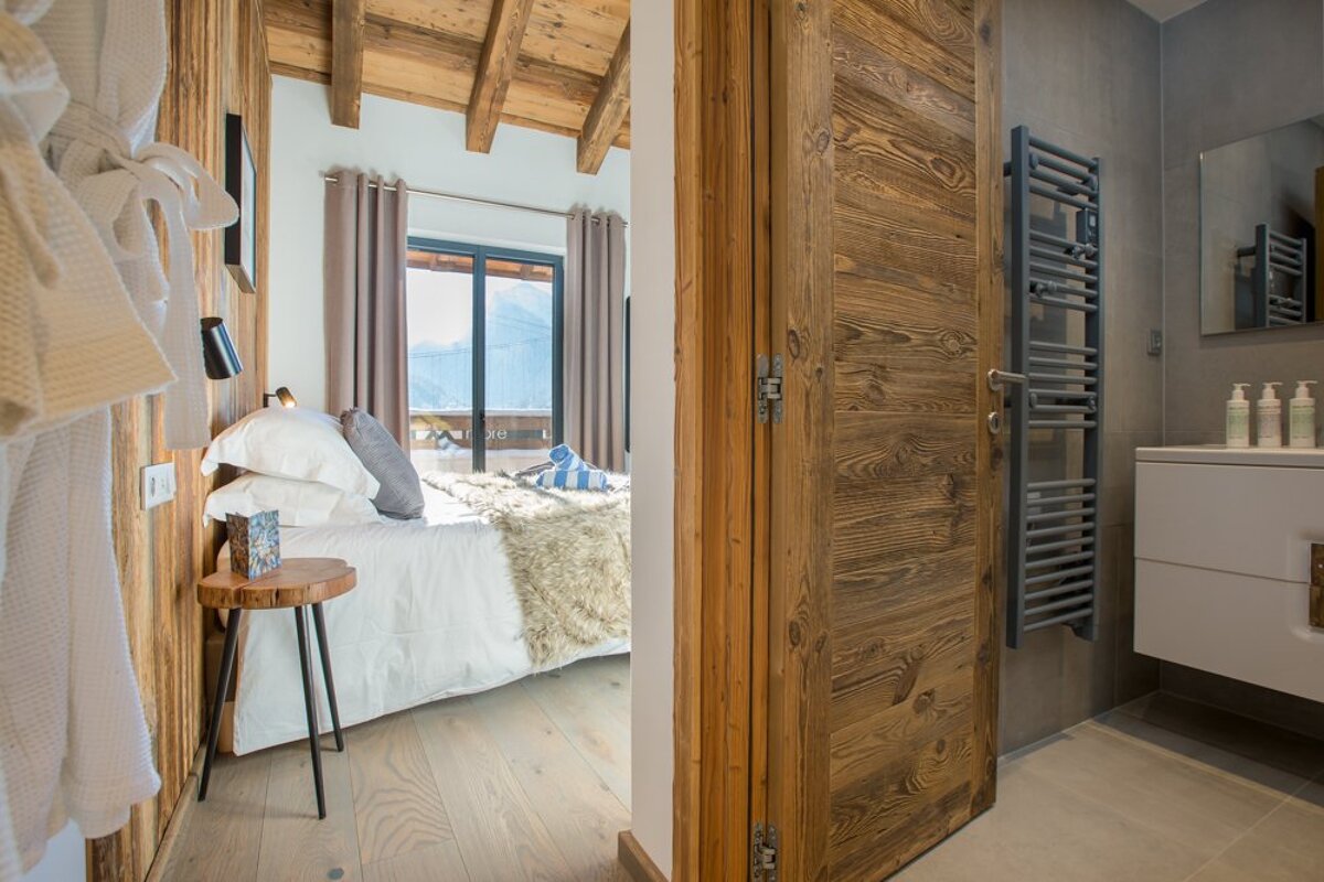 A bedroom with a bed and a bathroom with a towel rack