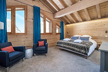 A bedroom with a king size bed and two chairs