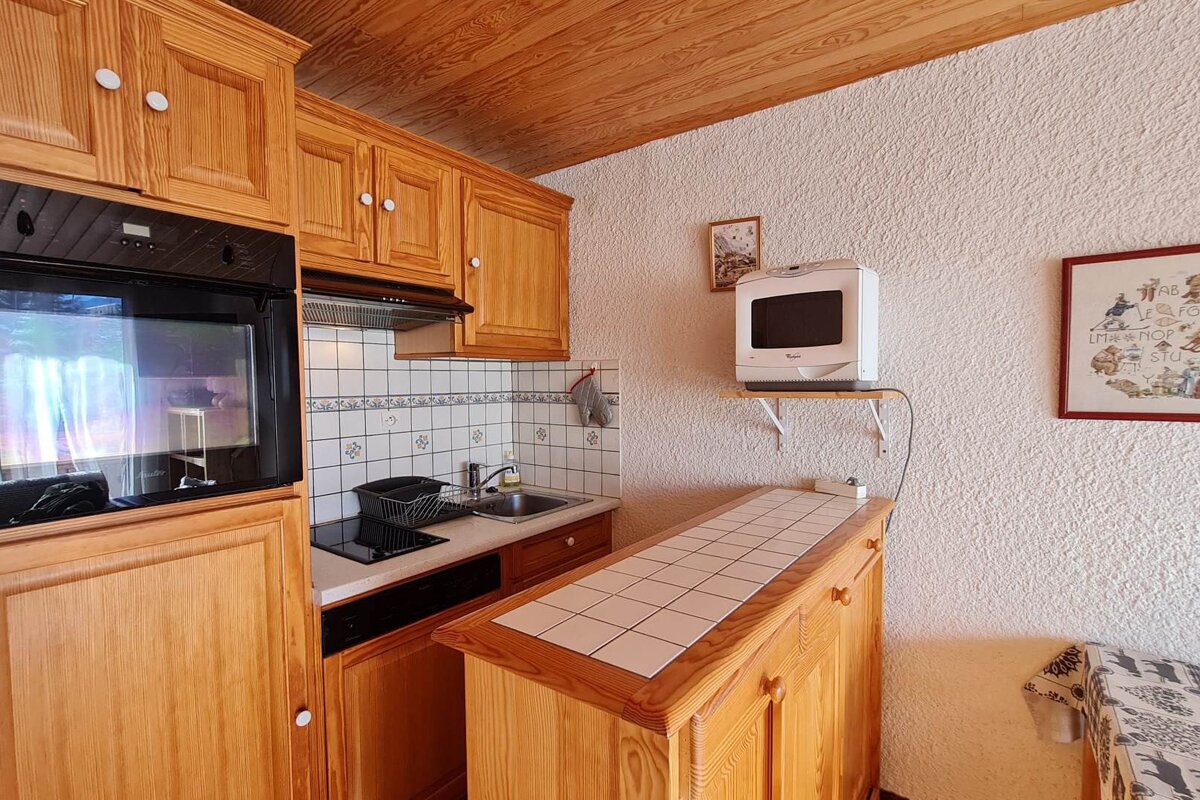 A kitchen with wooden cabinets and a microwave on a shelf