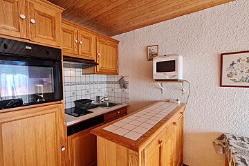 A kitchen with wooden cabinets and a microwave on a shelf