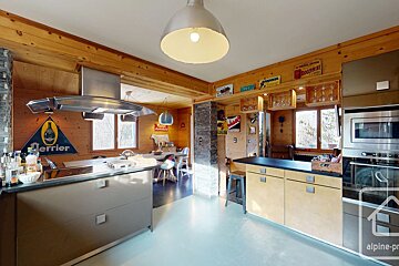 Bright, rustic wooden kitchen with modern appliances, a large island, vintage signs, and an open dining area.
