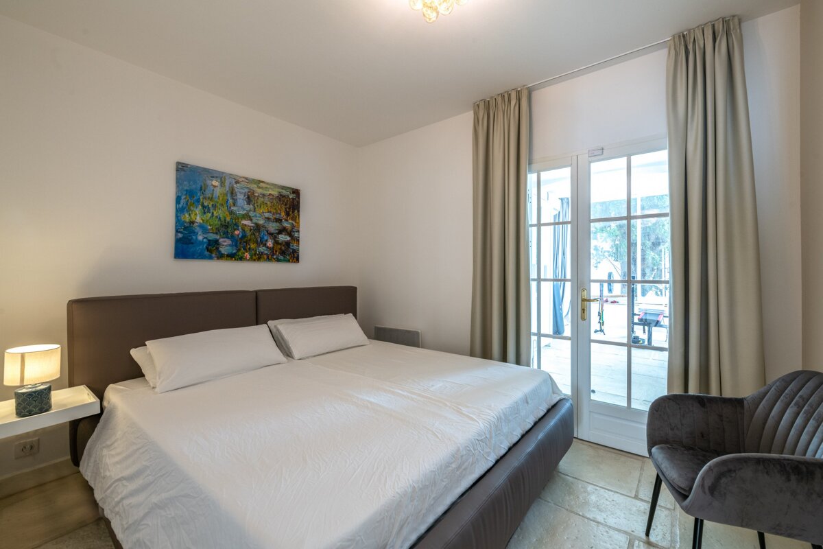 A bedroom with a painting on the wall above the bed