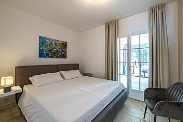 A bedroom with a painting on the wall above the bed