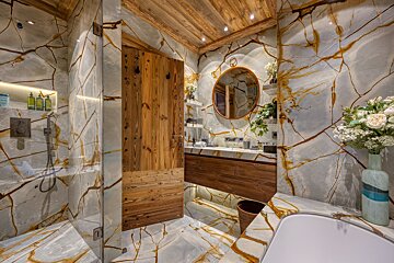 A bathroom with marble walls and a wooden door