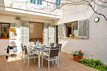 A patio with a table and chairs and a grill