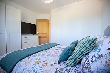 A bedroom with a bed a dresser and a flat screen tv