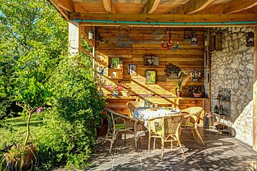 A patio with a table and chairs under a wooden roof