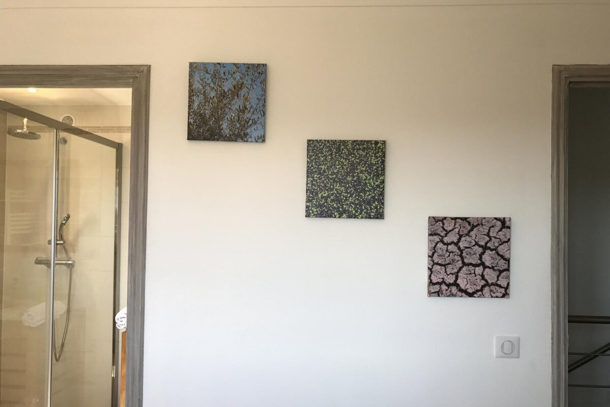 Three paintings hang on a white wall in a bathroom
