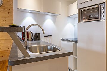 A kitchen with a sink and a clock that says 3:00