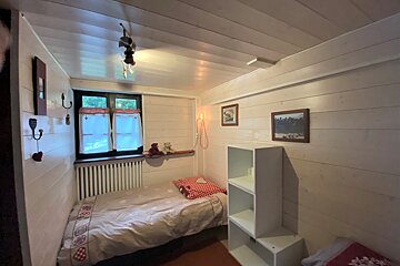 A small bedroom with a single bed and a bookshelf