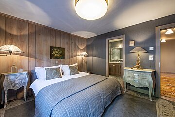A bedroom with a painting on the wall above the bed