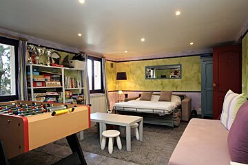 A room with a couch and a table with a foosball table