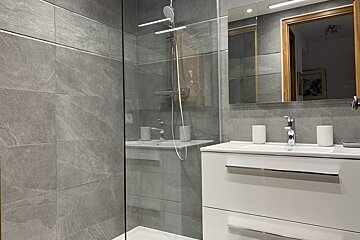 A bathroom with a walk in shower and a sink