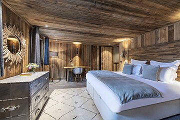 A bedroom with wooden walls and a large bed
