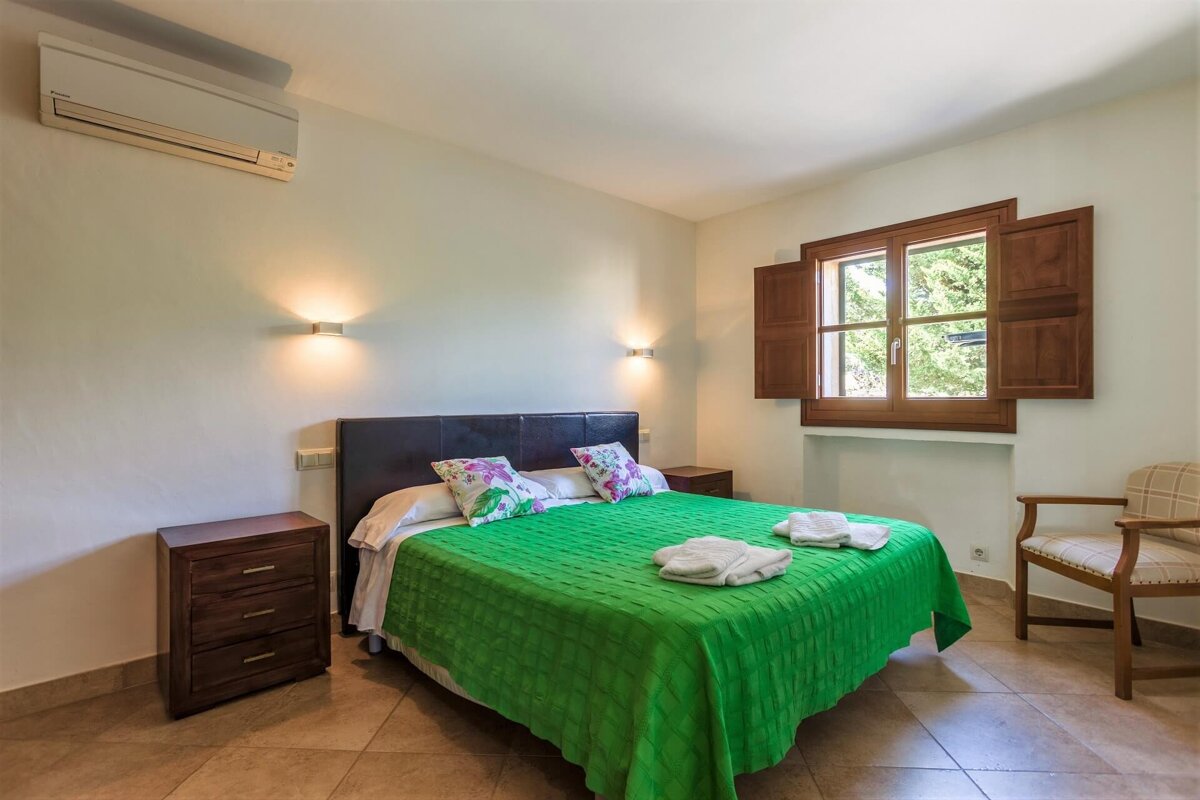 A bedroom with a green blanket on the bed
