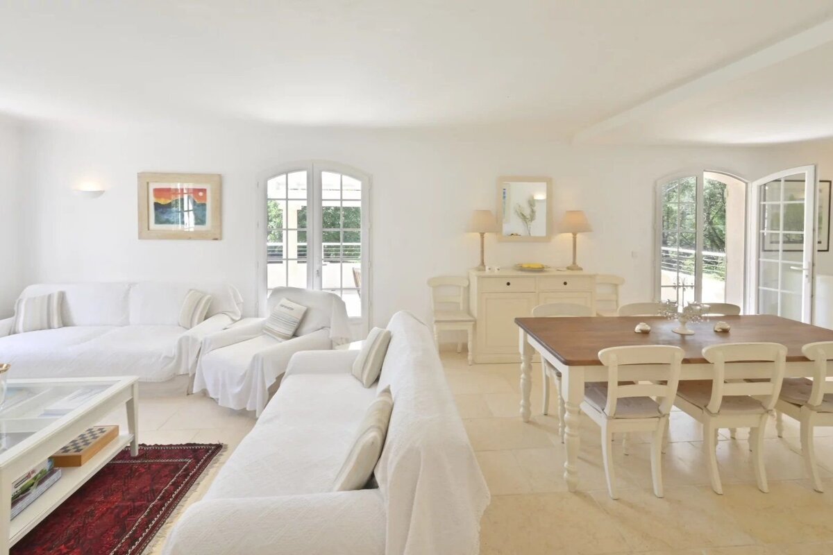 An open-plan living and dining area in a house with a predominantly white decor.