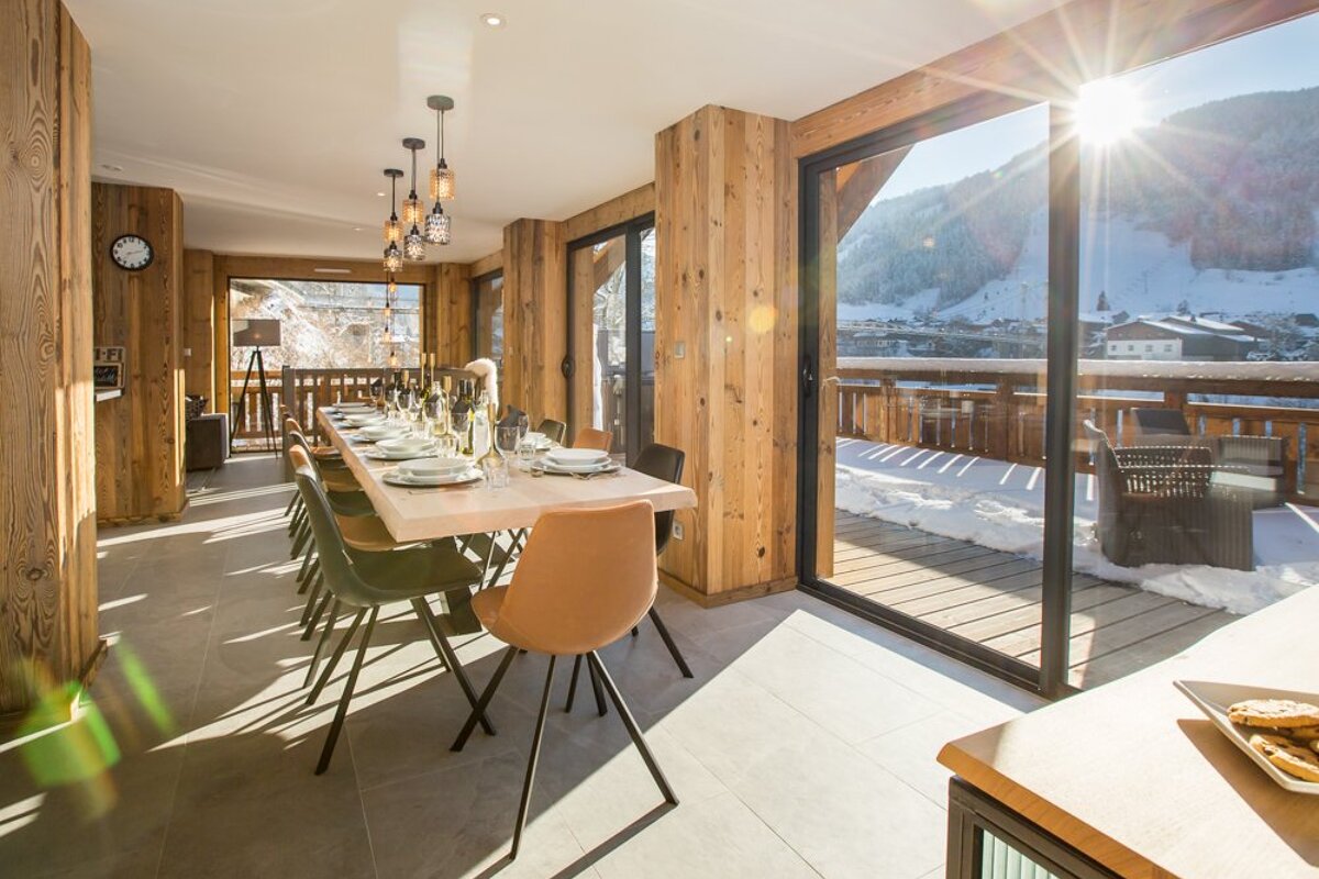 A dining room with a table and chairs and a clock on the wall