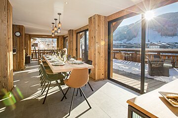 A dining room with a table and chairs and a clock on the wall