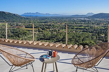 A balcony with two chairs and a table with a book on it