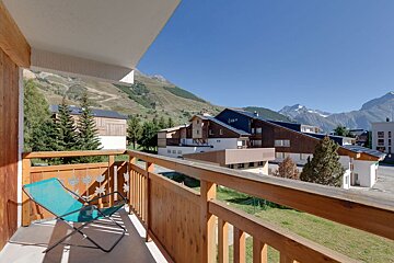 A balcony with a chair and mountains in the background
