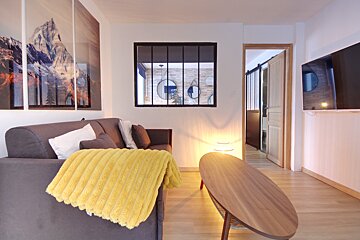 A living room with a yellow blanket on the couch