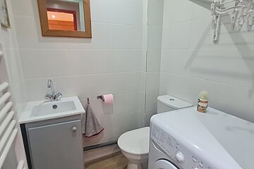 A bathroom with a washing machine and a toilet