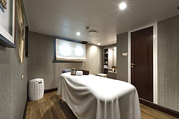 A room with a massage table and a laundry basket