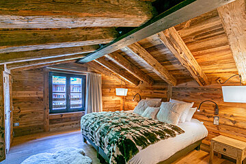 A bedroom with a wooden ceiling and a bed