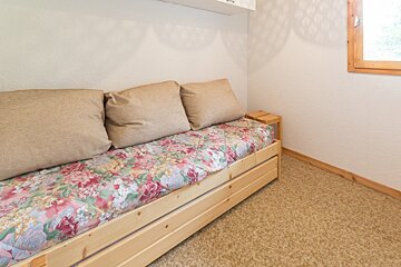 A wooden couch with a floral blanket and pillows