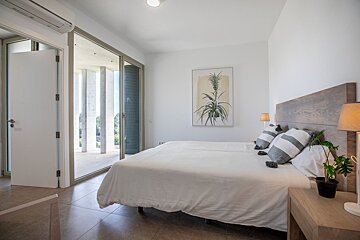 A bedroom with a large bed and a painting on the wall