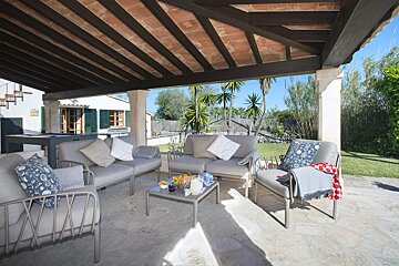 A patio with a couch and chairs under a wooden roof