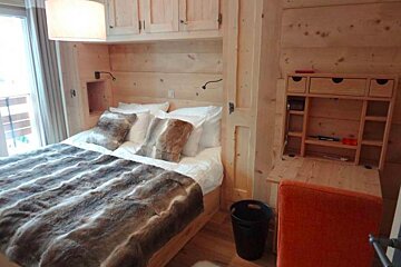 A bedroom with a bed and a desk with drawers