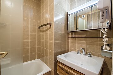 A bathroom with a bathtub and a sink and a hair dryer
