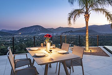 A table and chairs on a balcony with mountains in the background