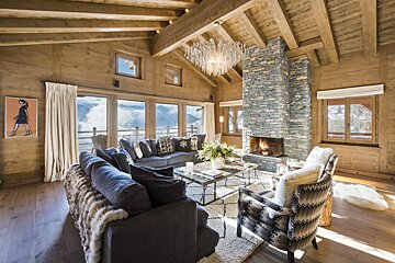 A living room with a stone fireplace and a chandelier
