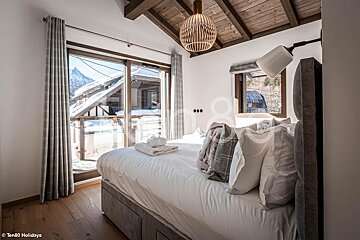 A bedroom with a large bed and a window with the word ten80 holidays on the bottom