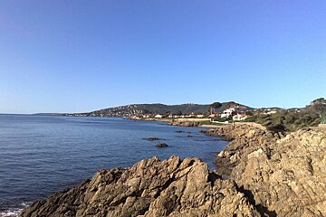 A cliff overlooking a body of water with houses in the distance
