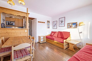 A living room with a red couch and a wooden table