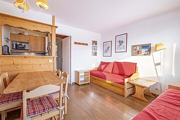 A living room with a red couch and a wooden table