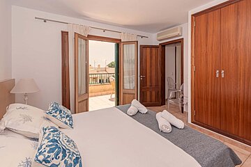 A bedroom with a king size bed and a balcony