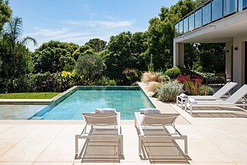 Two lounge chairs sit in front of a large swimming pool