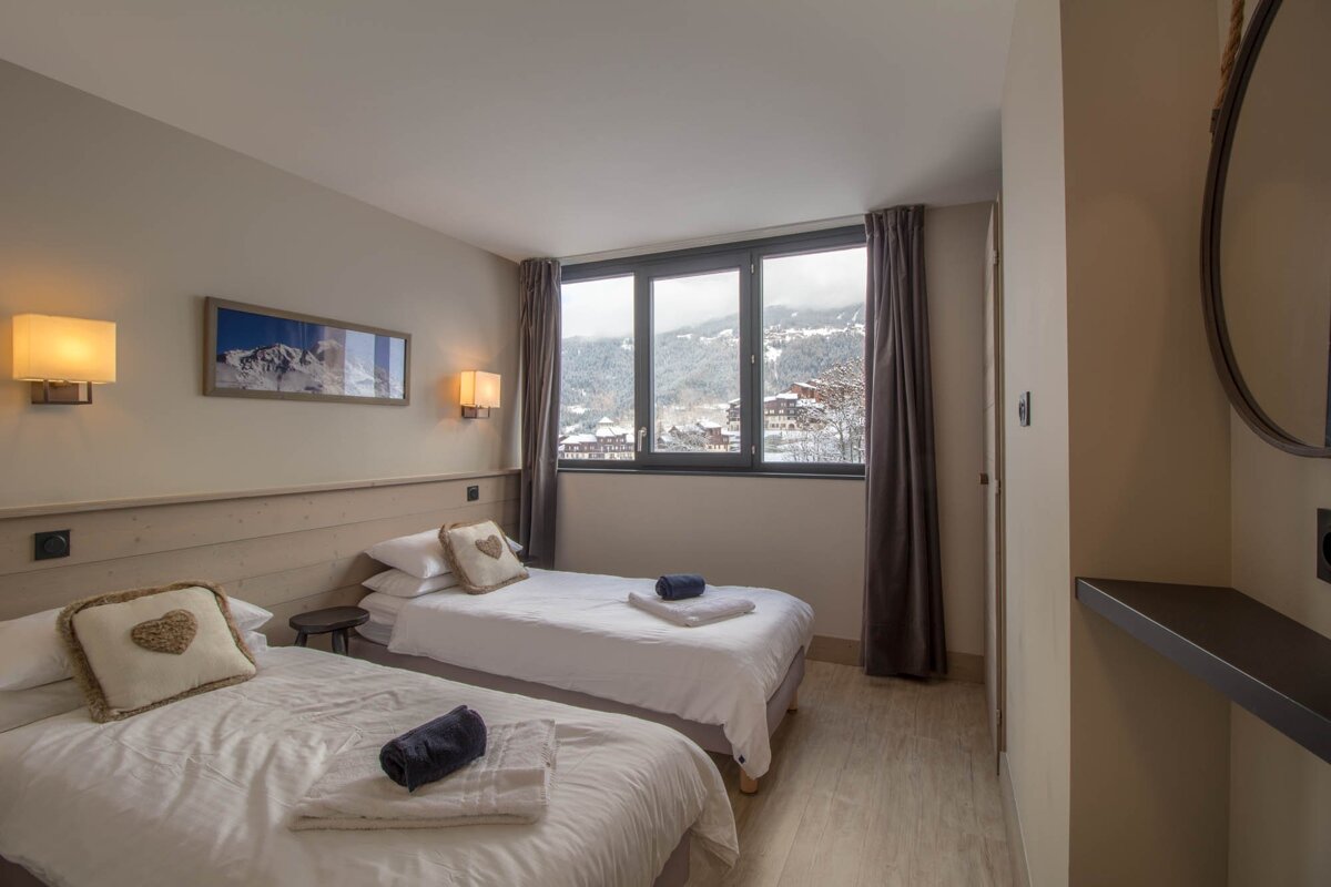 A hotel room with two beds and a large window