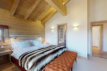 A bedroom with a large bed and a bench