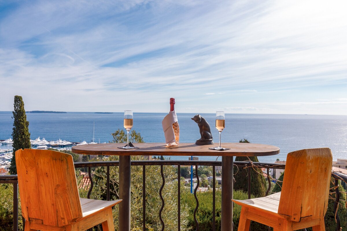 A table with two glasses and a bottle of wine on it overlooking the ocean