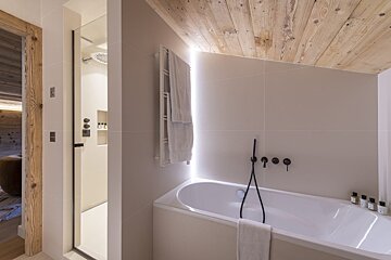 A bathtub in a bathroom with a wooden ceiling