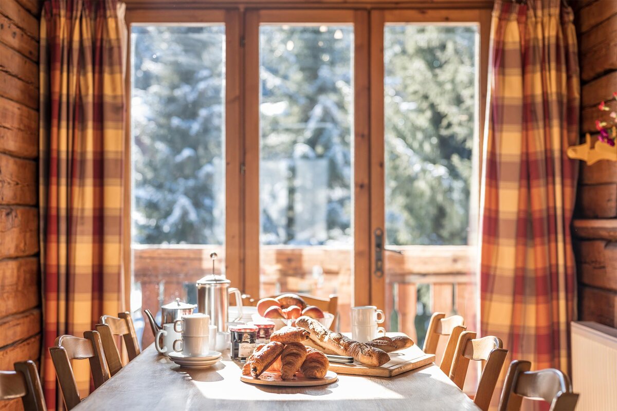 A wooden table with a plate of croissants on it