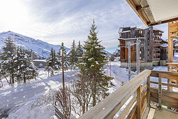 A balcony overlooking a snowy landscape with mountains in the background