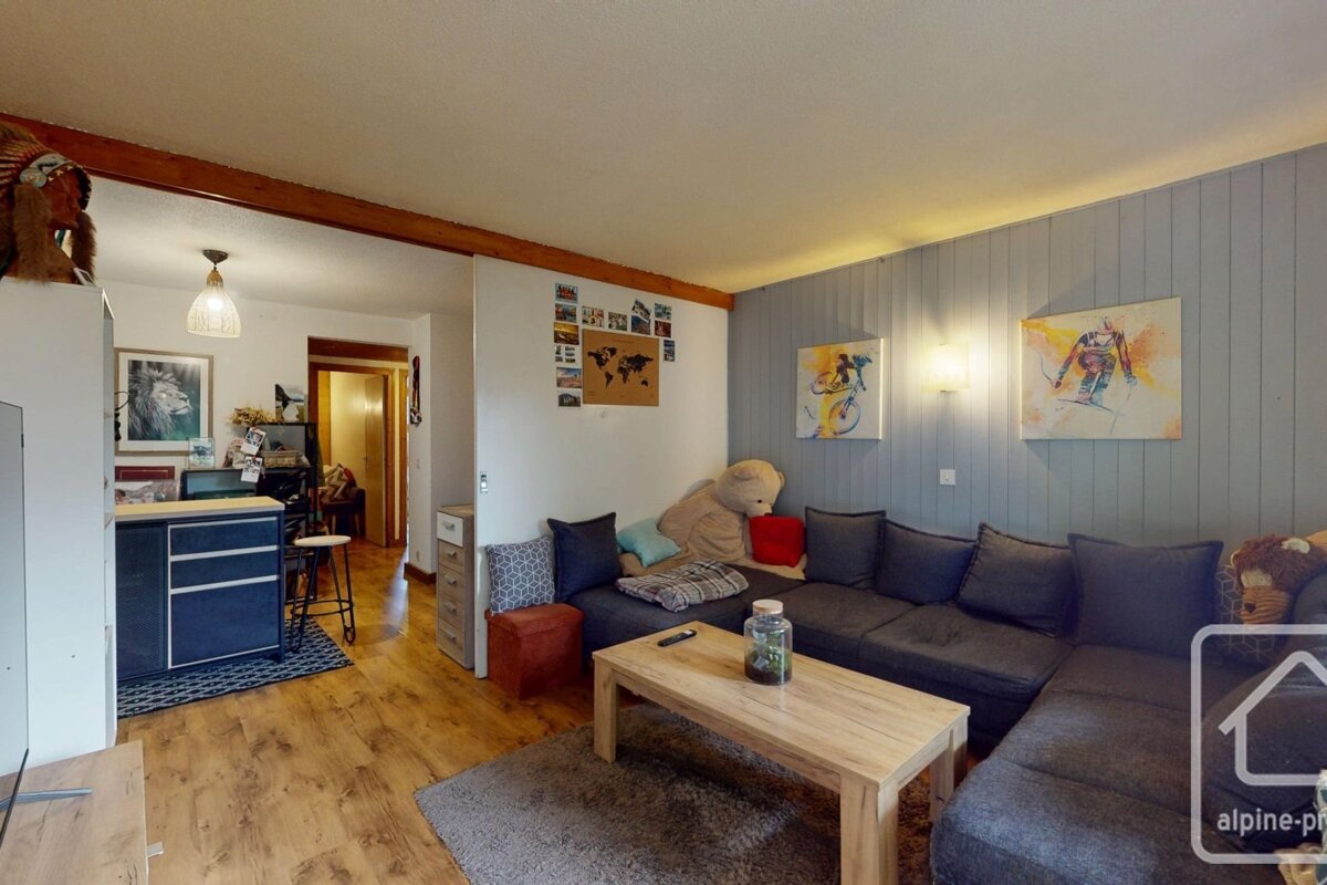 A cozy living room with a large grey sectional, a wooden coffee table, and light wood flooring.